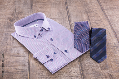Man's shirt folded and two ties on a wooden background
