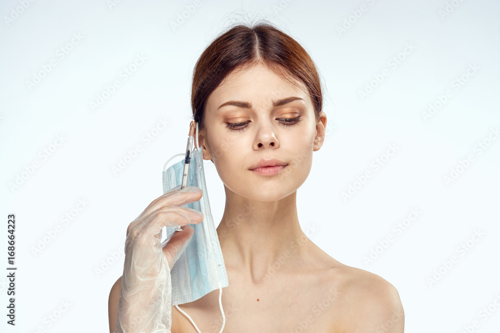 Beautiful woman on a white background, medical mask, portrait, syringe, beauty, plastic surgery Beautiful woman on a white background, medical mask, portrait, syringe, beauty, plastic surgery