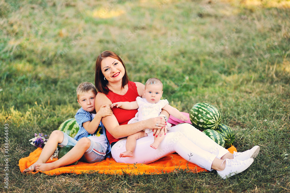 Family day concept, young mother with the son and daughter in summer city park Family day concept, young mother with the son and daughter in summer city park