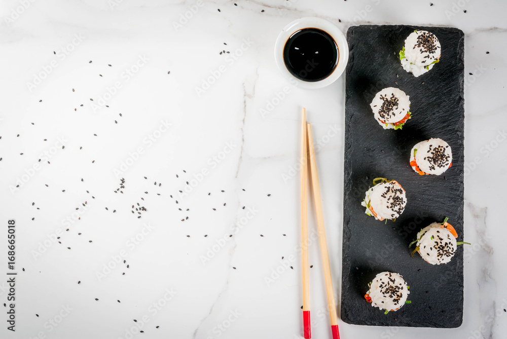 Trend hybrid food. Japanese Asian cuisine. Mini sushi-burgers, sandwiches with salmon, hayashi wakame, daikon, ginger, red caviar. White marble table, with chopsticks, soy sauce. Top view copy space Trend hybrid food. Japanese Asian cuisine. Mini sushi-burgers, sandwiches with salmon, hayashi wakame, daikon, ginger, red caviar. White marble table, with chopsticks, soy sauce. Top view copy space