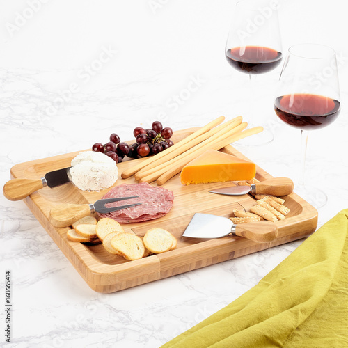 Photo Bamboo wood serving tray with cheese and meats