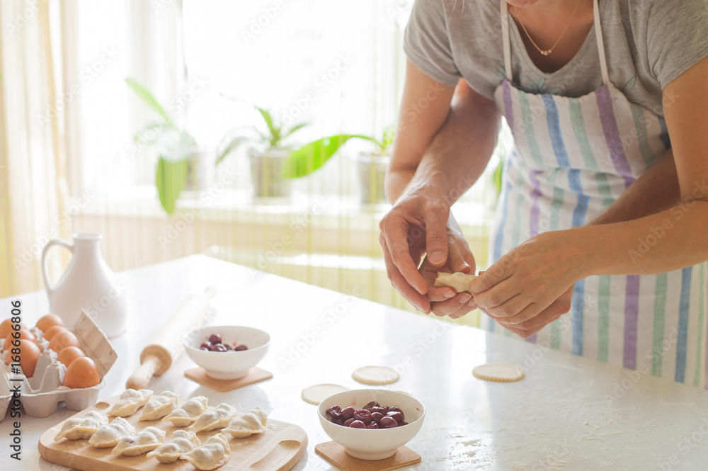 Family couple cook dumplings with cherry (vareniki) in four hand Family couple cook dumplings with cherry (vareniki) in four hand