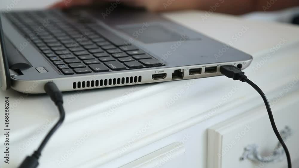 Female hand inserting USB cable into laptop Female hand inserting USB cable into laptop