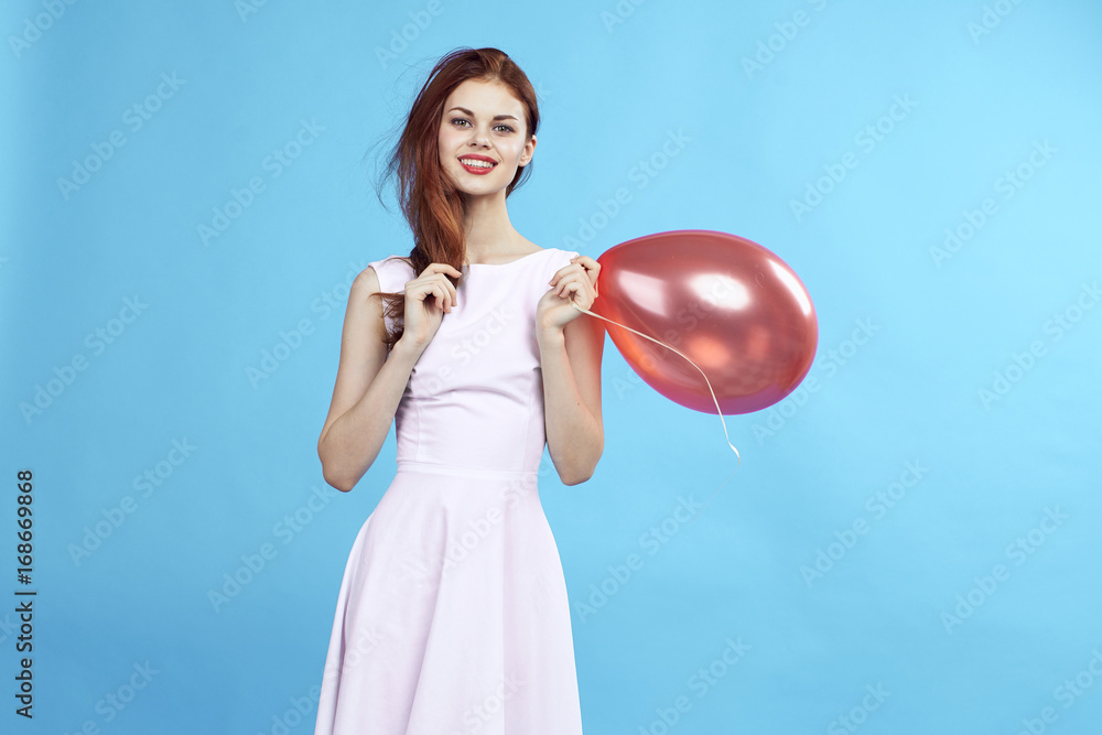 Beautiful woman on a blue background in a dress holding a balloon