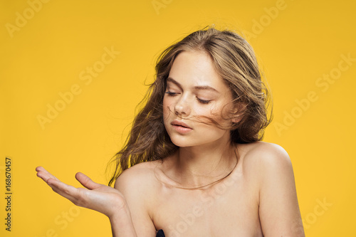 Beautiful woman on a yellow background shows a blank space  portrait