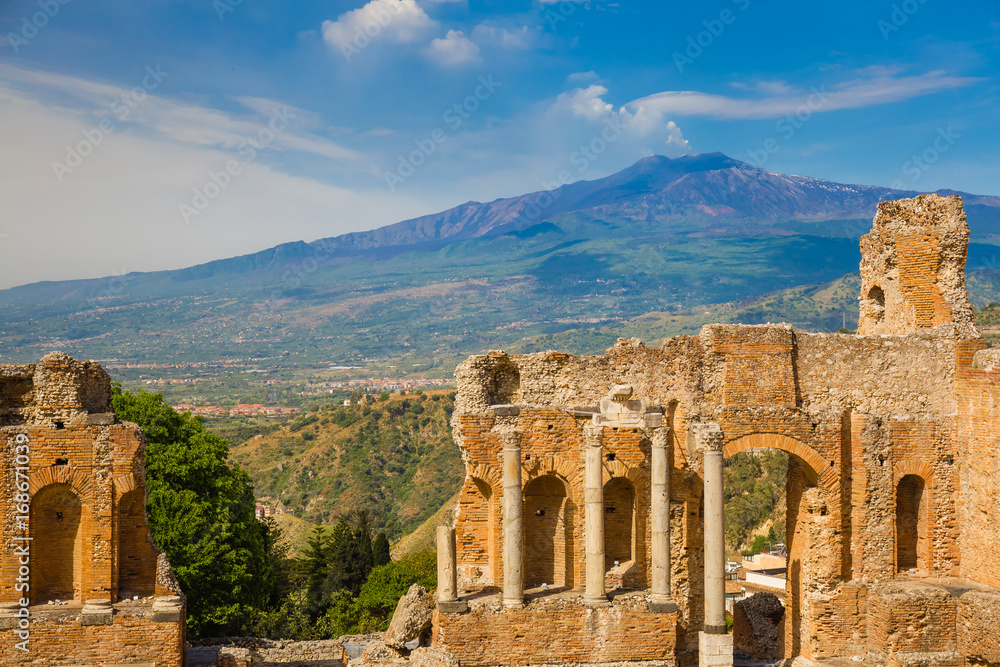 Panoramic view of beautiful town of Taormina with its greek amphitheatre and Etna volcano background, Sicily island, Italy