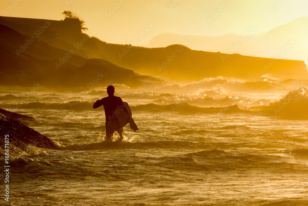 Bodyboarder walkimg in the water at Ipanema tropical sunrise in Rio de Janeiro