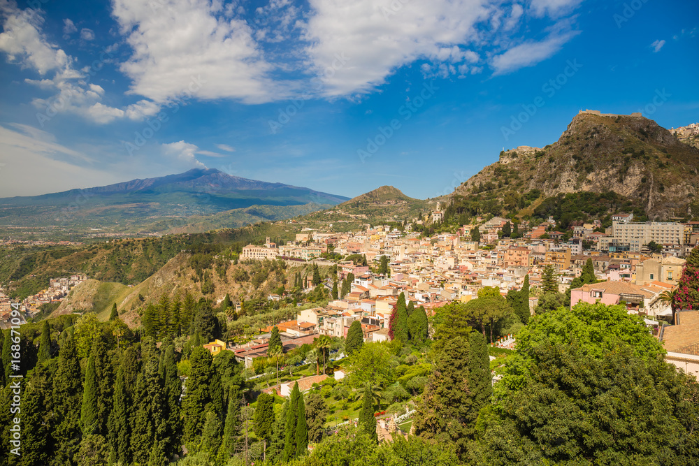 Panoramic view of beautiful town of Taormina, with green foreground and blue sky, Sicily island, Italy