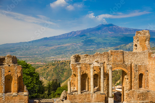 Panoramic view of beautiful town of Taormina with its greek amphitheatre and Etna volcano background, Sicily island, Italy