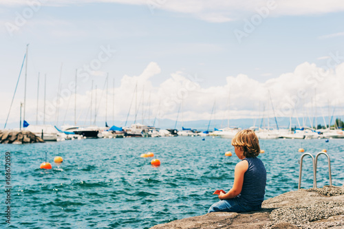 Funny little boy resting by lake Geneva in a small Lutry port, Switzerland. Back view © annanahabed