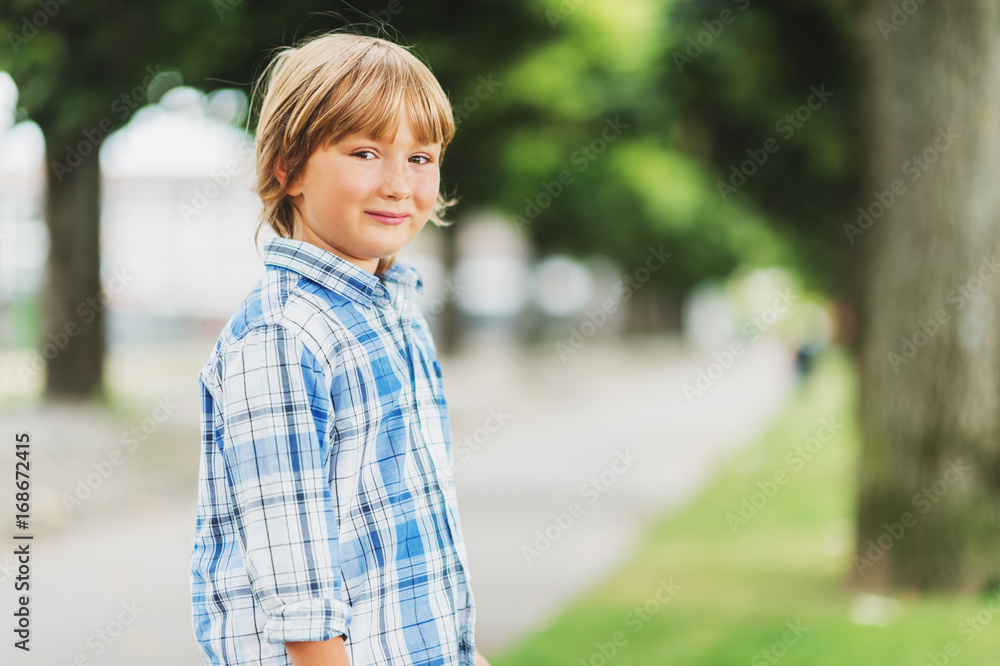 Outdoor fashion portrait of cute little 6 year old boy wearing blue plaid casual shirt Outdoor fashion portrait of cute little 6 year old boy wearing blue plaid casual shirt