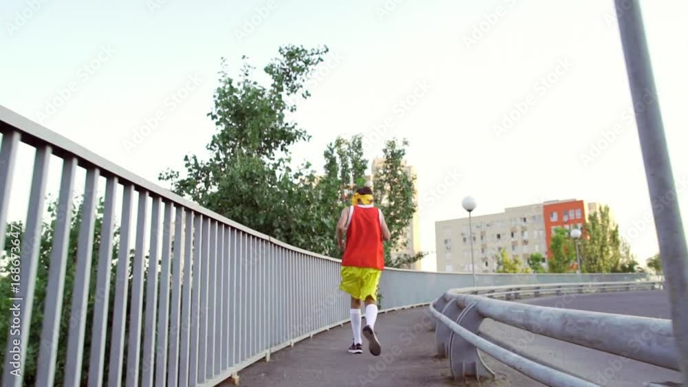Funny thin guy in sports clothes jogging on the bridge in the morning. Funny thin guy in sports clothes jogging on the bridge in the morning.