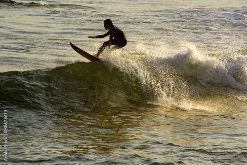 Canvas Print Boy surfing at sunset on Arpoador beach in Ipanema