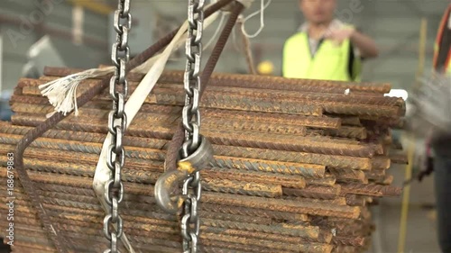 Silver Chain Moving Through Tied Up Bundle Of Rusty Steel Bars - Close Up 