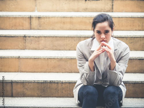 Upset young caucasian beautiful businesswoman tired from work sitting at stairs, unemployment, fired from job, disappointed, loss and feeling down concept photo