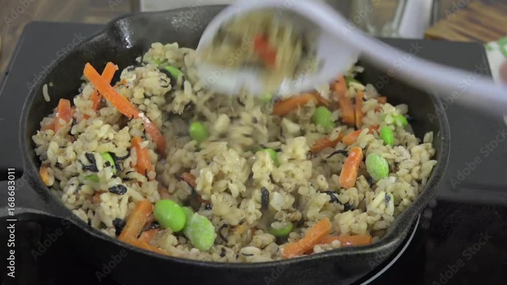 Stir fried rice with edamame, carrots, cooking in a cast iron skillet Stir fried rice with edamame, carrots, cooking in a cast iron skillet