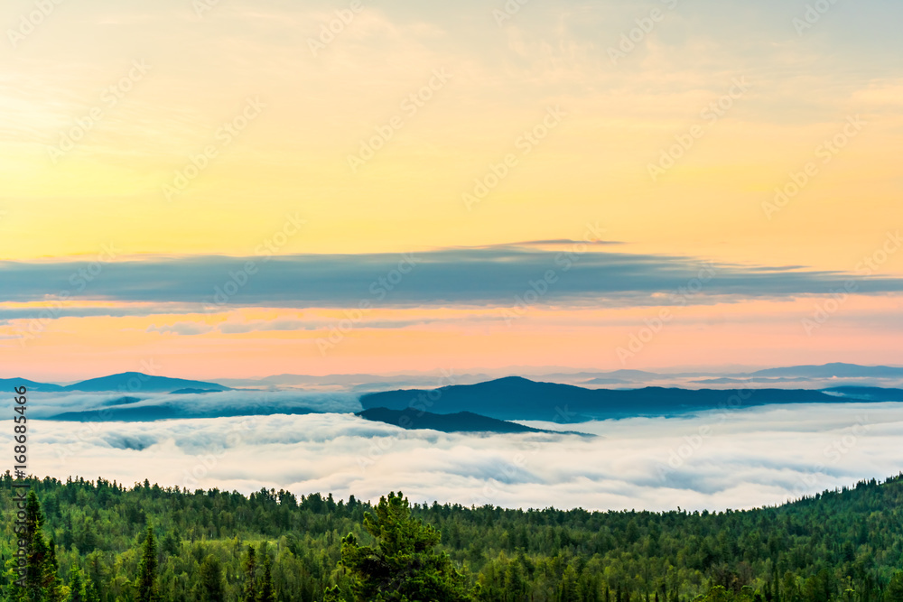 Morning mist over the tops of mountains and woods at spectacular sunrise