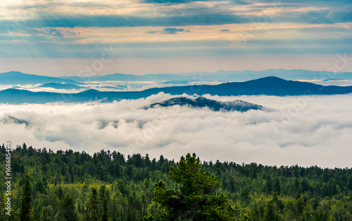 Morning mist over the tops of mountains and woods at spectacular sunrise