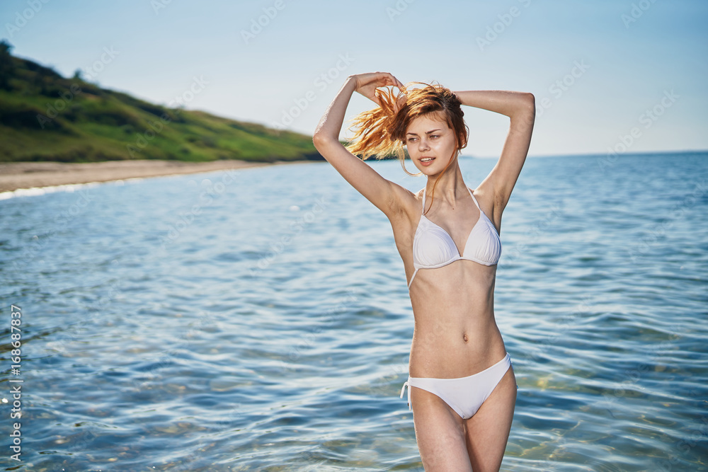 Woman in a white bathing suit on the beach of the sea, summer, vacation, sun