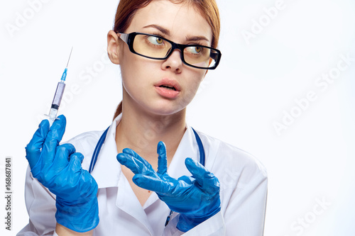Woman in glasses and in medical gown holds a syringe on white isolated background  portrait