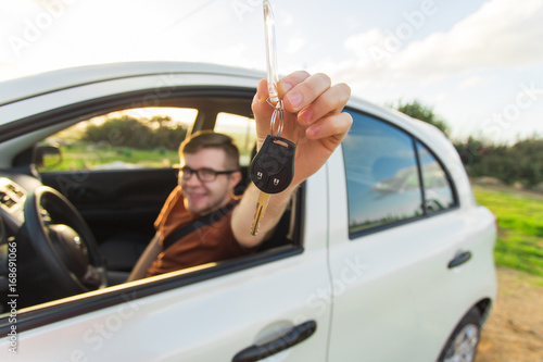 Young man smiling and holding key in his car. Auto purchase and people concept © satura_