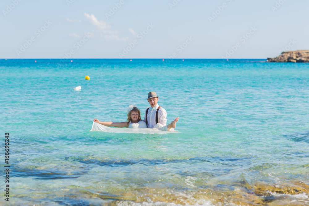 Fototapeta premium Bride and groom having fun at sandy tropical beach