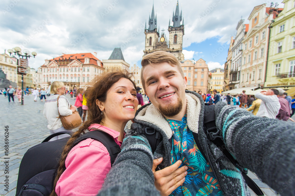 Obraz premium Happy young couple in love takes selfie portrait in Prague, Czech Republic. Pretty tourists make funny photos for travel blog in Europe.