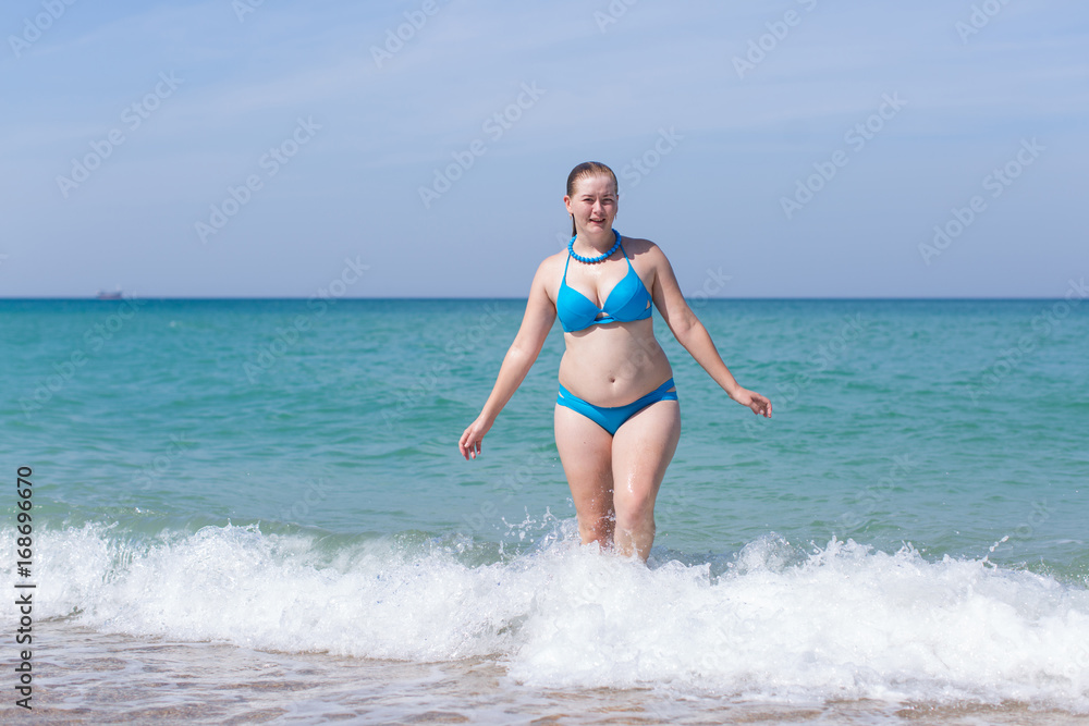Overweight middle aged woman comes from sea water Overweight middle aged woman comes from sea water
