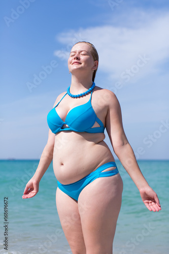 Wet overweight middle aged woman in blue bikini