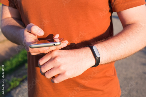 Sport, gadget, activity tracker and people concept - Male runner jogging outside looking at his wearable fitness bracelet close up