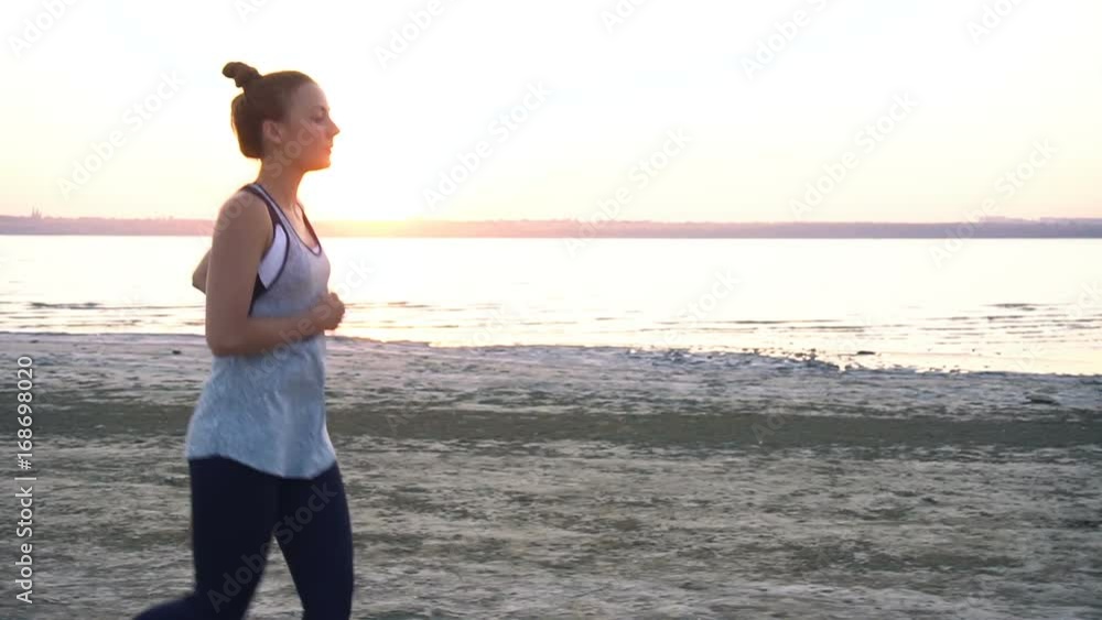 Woman jogs at sunrise, early morning exercise on the shore Woman jogs at sunrise, early morning exercise on the shore