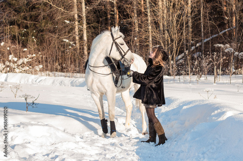 Nice girl and white horse in a forest in a winter