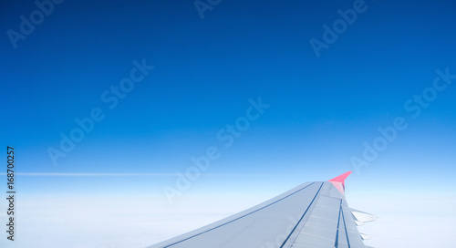Wing of an airplane flying above the clouds. © familylifestyle