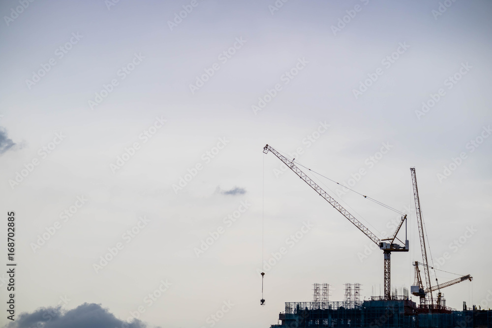 Crane and construction site building with twilight evening sky