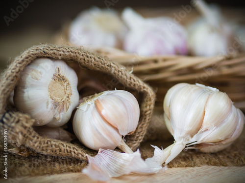 Closeup garlic clove, garlic bulb in wicker basket place on hemp sack background