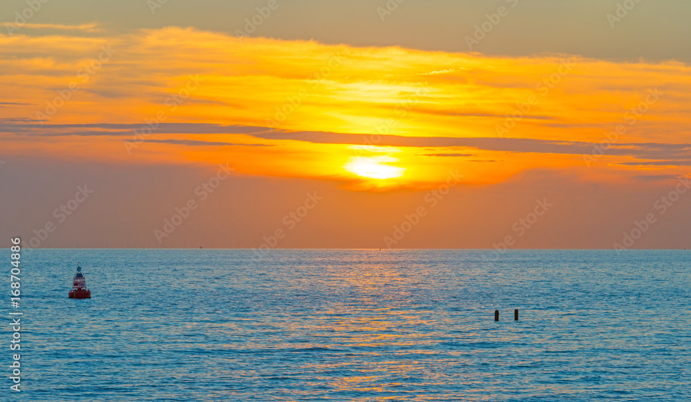 Sea along a sandy beach in the light of sunset in summer