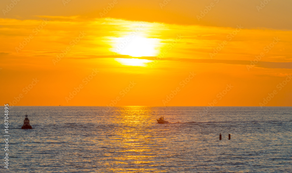 Sea along a sandy beach in the light of sunset in summer