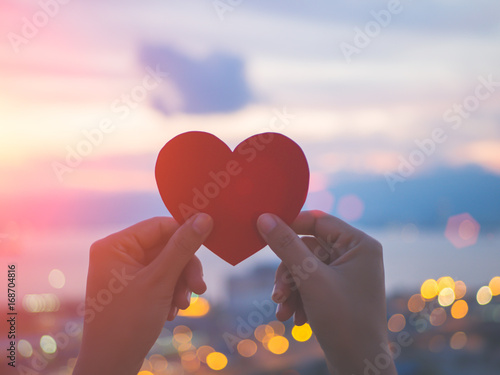 Soft focus hand holding beautiful heart during sunset background. Happy, Love, Valentine's day idea, sign, symbol, concept.