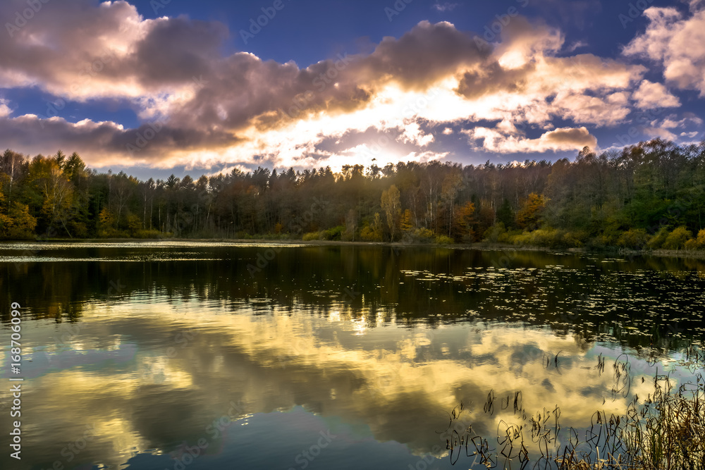 Sunset sky over lake, sun fall in the forest, autumn landscape