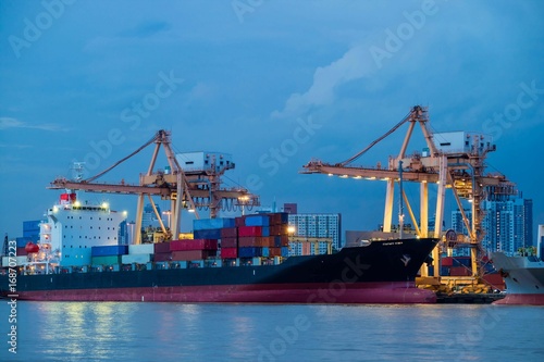 Container loading by crane, cargo ship at shipping port at twilight, Logistics and transportation concept