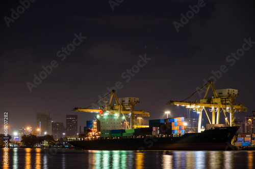 Container loading by crane, cargo ship at shipping port at twilight, Logistics and transportation concept