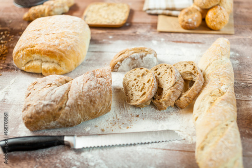 Fresh bread slice and cutting knife on rustic wooden table