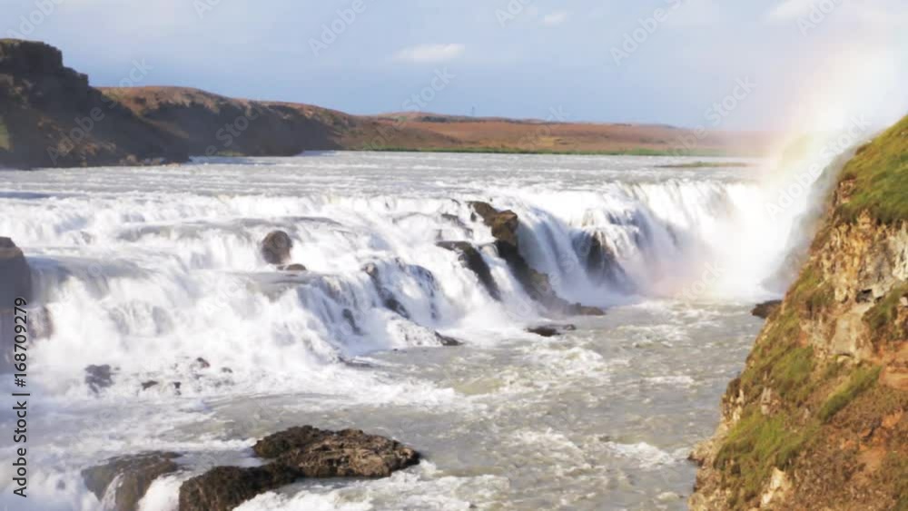 Iceland - famous waterfall Gullfoss. Summer day, rainbow, water stream and water cloud of splashes. Iceland - famous waterfall Gullfoss. Summer day, rainbow, water stream and water cloud of splashes.