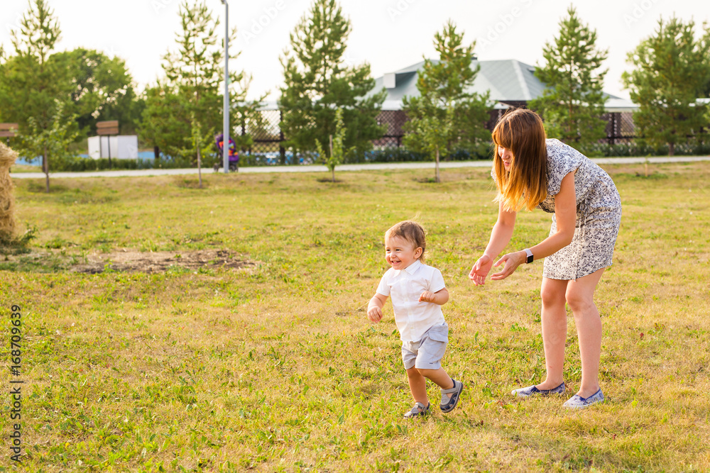 Cute cheerful child with mother play outdoors in park