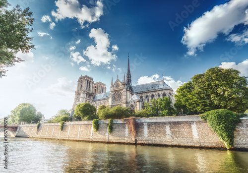 Notre Dame Cathedral in Paris, France, on a sunny day with the river Seine and dramatic clouds. Scenic skyline.