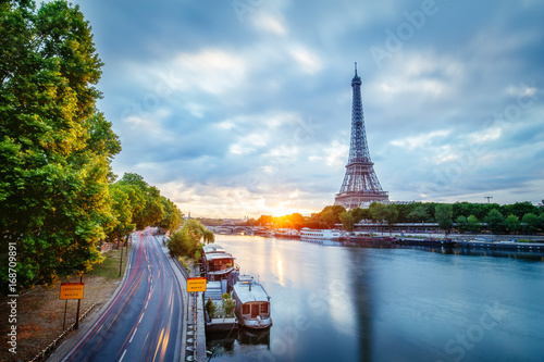 Scenic view over the Eiffel Tower from a bridge at sunrise. Paris, France. Beautiful travel background with rising sun and dramatic clouds. © Funny Studio