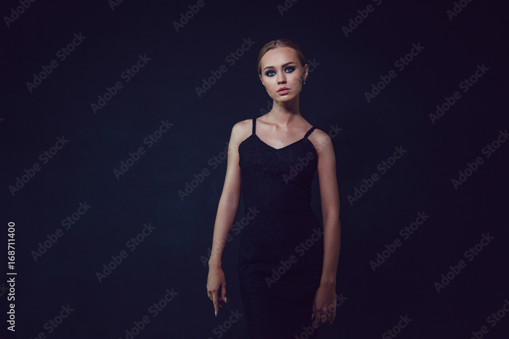 Attractive woman in black cocktail dresses on a dark background.