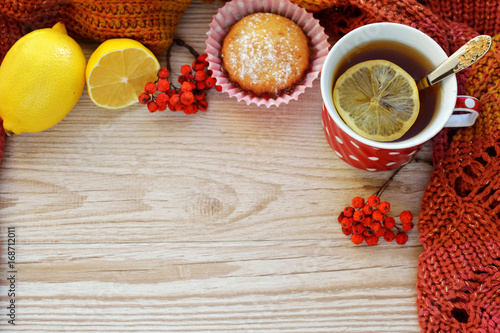 Mug of hot black tea with lemon and homemade cakes (cupcake) on a wooden light background photo