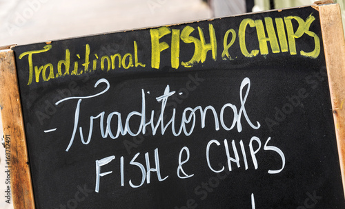 Close up on a fish and chips sign, text Traditional fish and chips written on a blackboard in the street photo