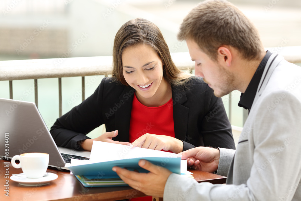 Obraz premium Executives consulting documents in a coffee shop